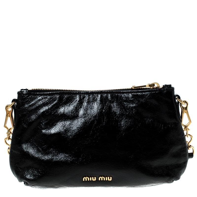 The Miu Miu Pochette blends elegance with contemporary style. The black leather exterior is adorned with a bow detail to create a feminine appearance. The bag has gold-toned hardware, top-zip closure and removable shoulder strap. The bag has a