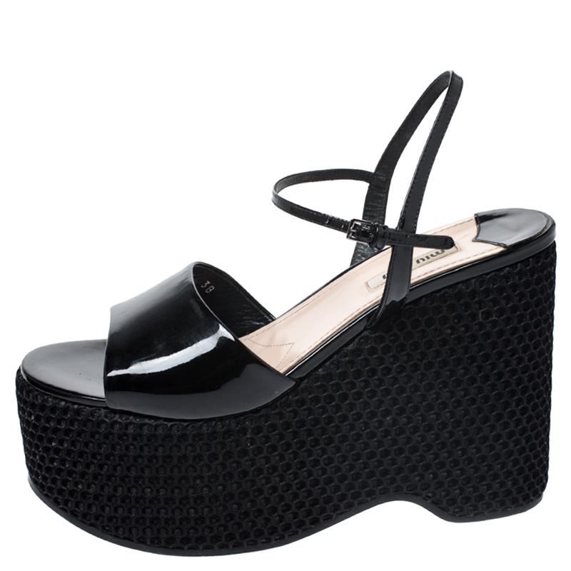 These stylish sandals come from the house of Miu Miu. They are crafted in Italy and made from glossy patent leather and come in black. They feature open toes, buckled ankle straps, 6 cm platforms and 12 cm wedge heels. They are finished with