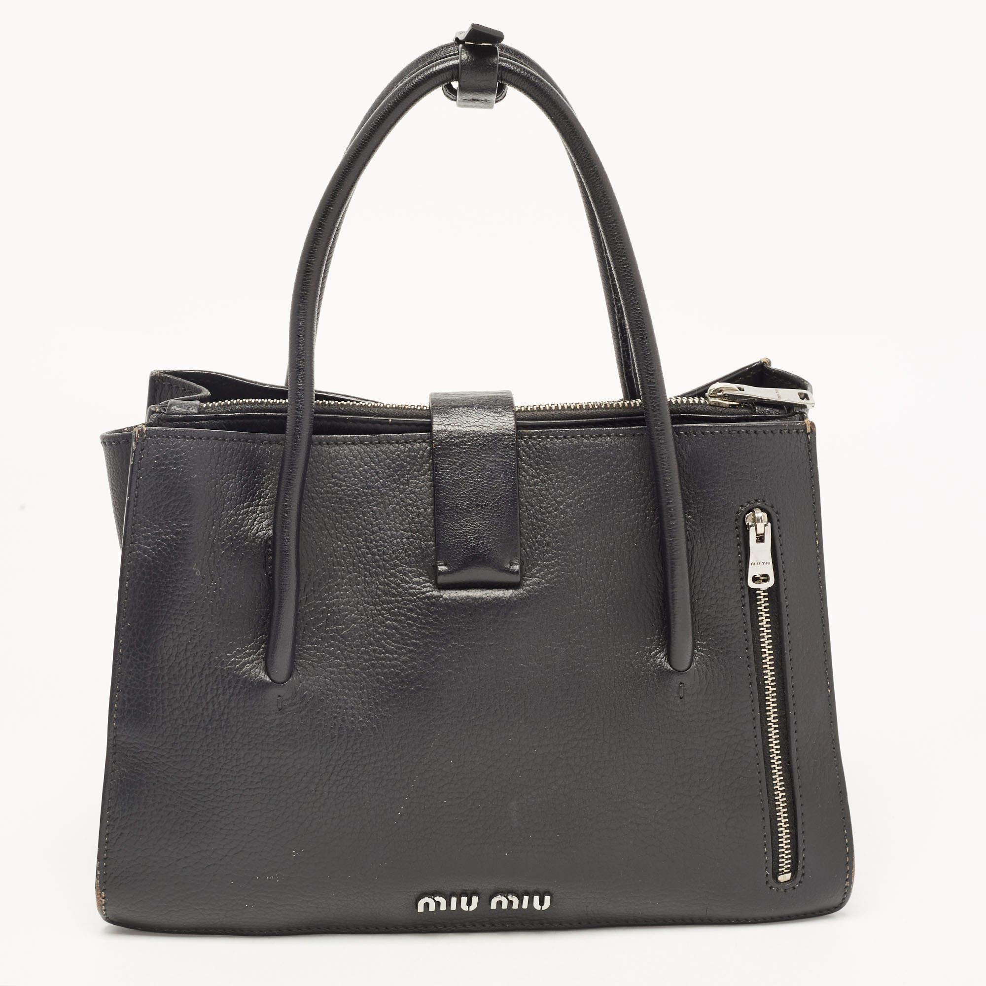 Made from black leather, this Miu Miu tote brings a spacious size and a refined appeal. It features two handles, an optional strap, silver-tone hardware, push-lock detailing, and lined compartments.

Includes: Detachable Strap