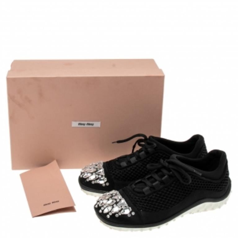 Signées Miu Miu, ces baskets basses pour femme sont réalisées en maille et en satin et ornées de cristaux sur les orteils. Ils sont fixés par des lacets et montés sur des semelles en caoutchouc durables.