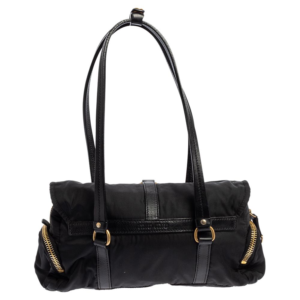 This lovely bag comes from the house of Miu Miu. Crafted from quality nylon & leather, it flaunts a lovely shade of black. The exterior is beautified with gold-tone hardware. The bag opens to reveal a spacious fabric interior. This bag will make