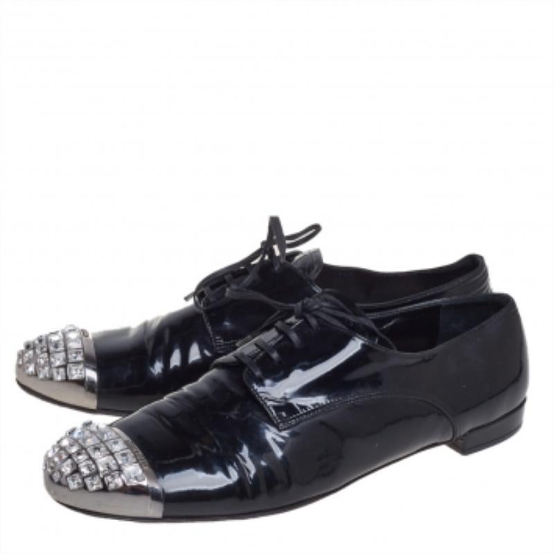To perfectly complement your attires, Miu Miu brings you this pair of oxfords that speak nothing but style. They have been crafted from black patent leather and styled with crystal-embellished cap toes and lace-ups on the vamps. They are endowed