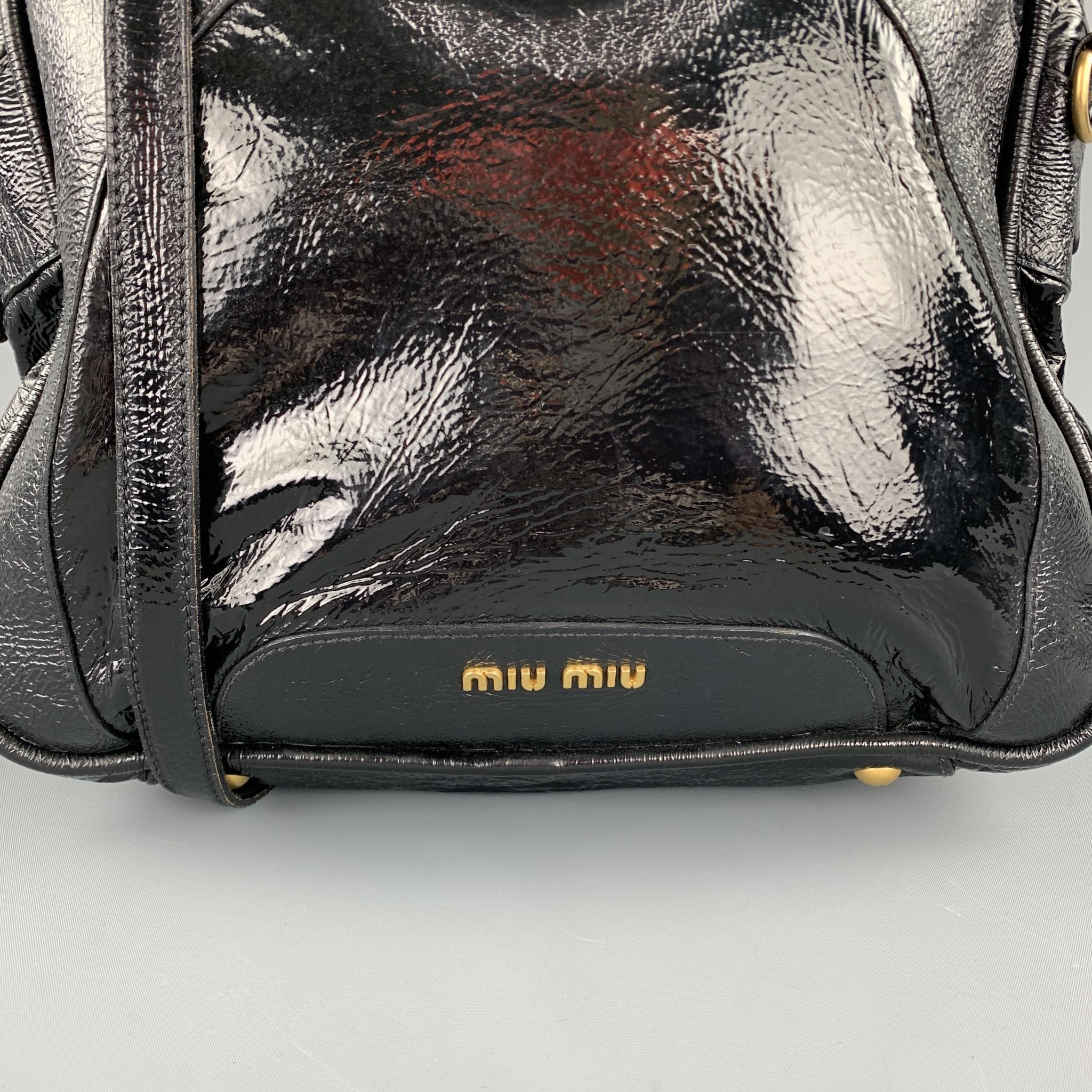 MIU MIU handbag comes in a black patent leather with gold toned hardware featuring a shoulder strap detail, top handles, inner zipper pocket, and a zip up closure. Made in Italy.

Good Pre-Owned Condition.

Measurements:

Length: 11 in.
Width: 13