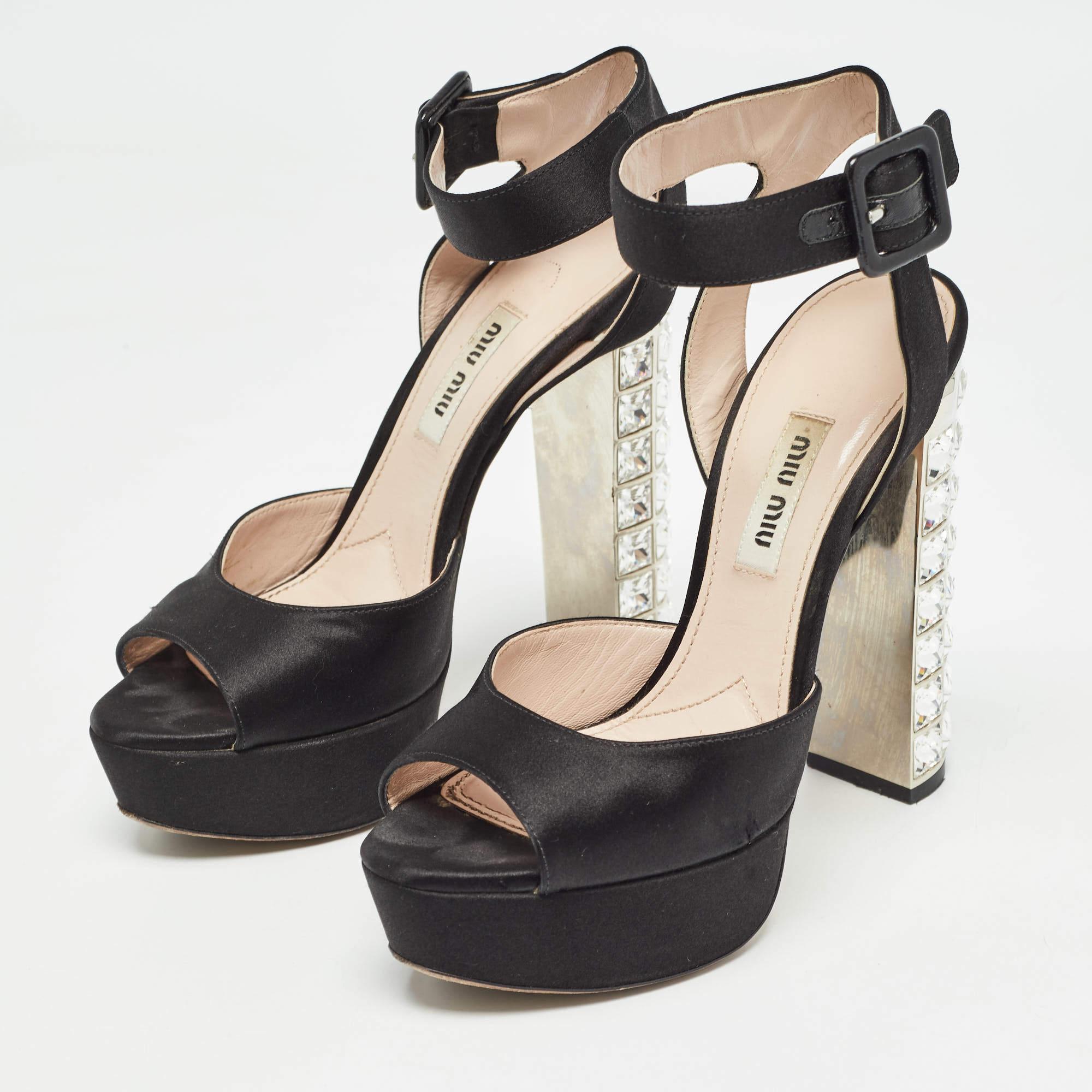 The charm and glamour of these Miu Miu sandals will certainly make your heart flutter. They are crafted with satin in a classic black hue. This stylish pair comes with an ankle strap secured with buckle fastenings leather lined interior and high