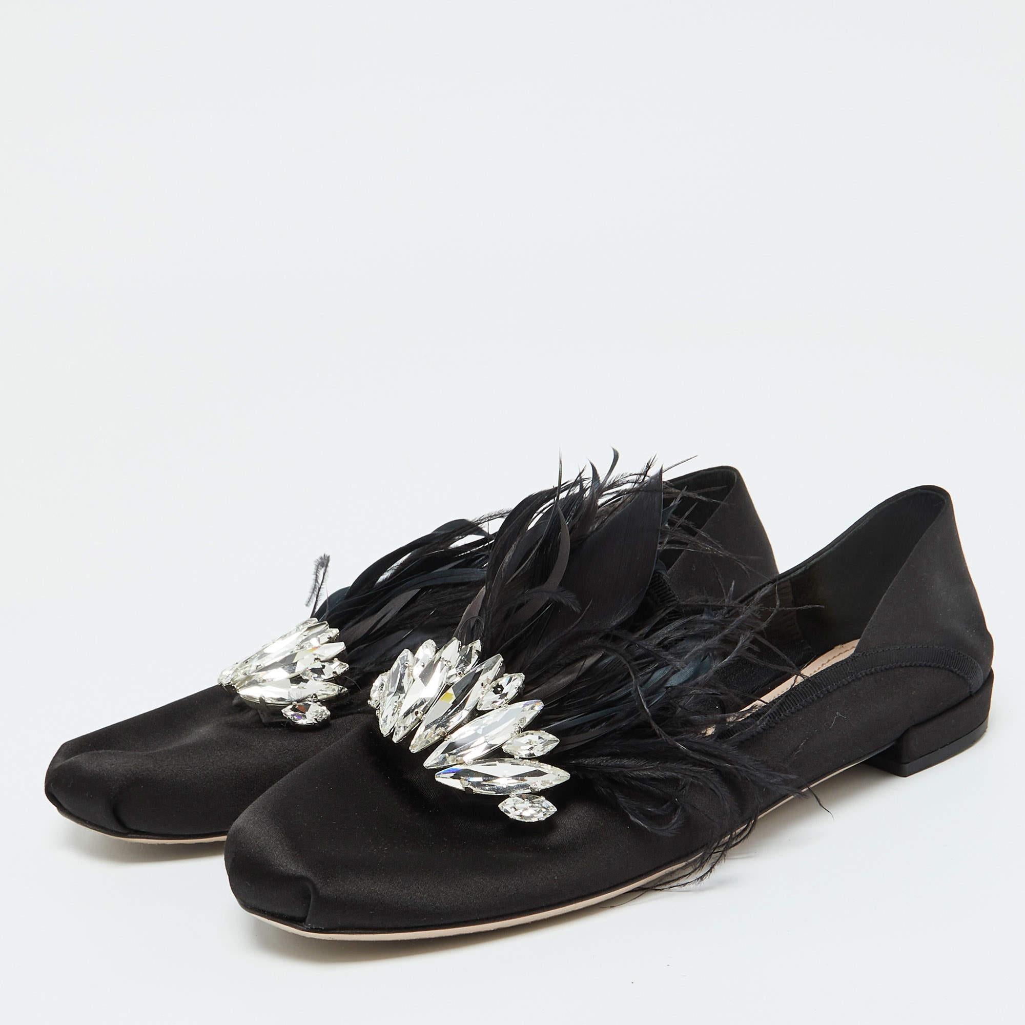 Estas zapatillas de fumar de Miu Miu presentan un diseño encantador. De satén  Los toboganes tienen puntera redonda y la parte superior está decorada con plumas y cristales. Llevan plantillas forradas de piel con la etiqueta de la marca. Llévelos