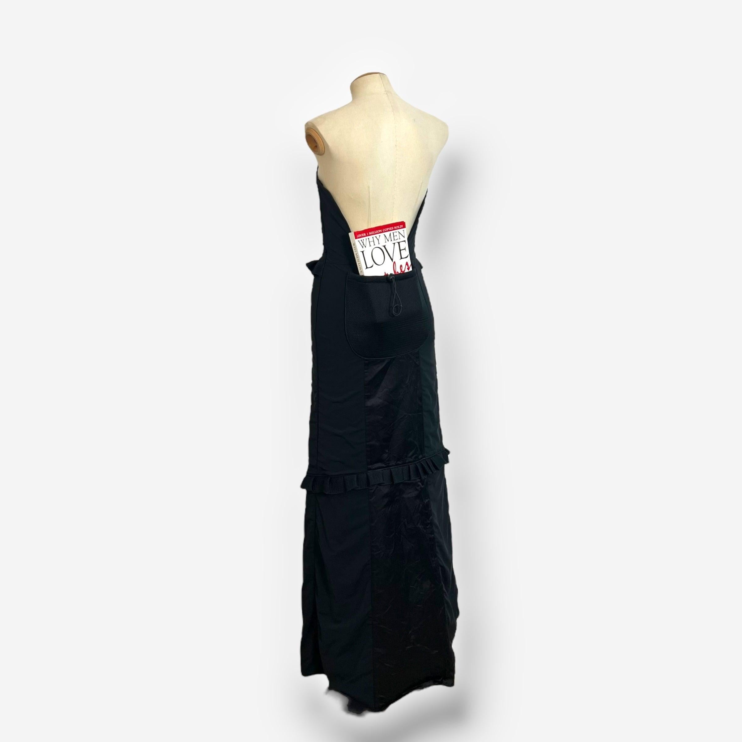 A striking piece from Miu Miu's Fall/Winter 1999 runway collection, this strapless black maxi dress features sculptural elegance with delicate ruffle trim at the bust, waist, and lower skirt. Originally presented in brown as Look 42 on the runway,