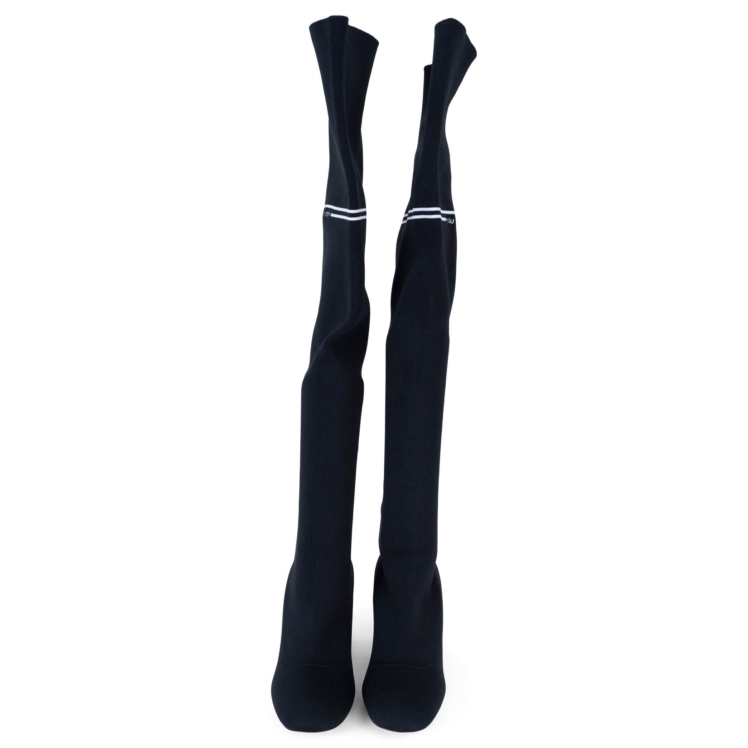Cette botte Miu Miu 100 % authentique est réalisée en maille technique noire et dotée d'une bande logo blanche contrastante sur le dessus. Elles sont dotées de bouts ronds, d'une tige au-dessus du genou et d'un talon bloc recouvert de daim. Cette