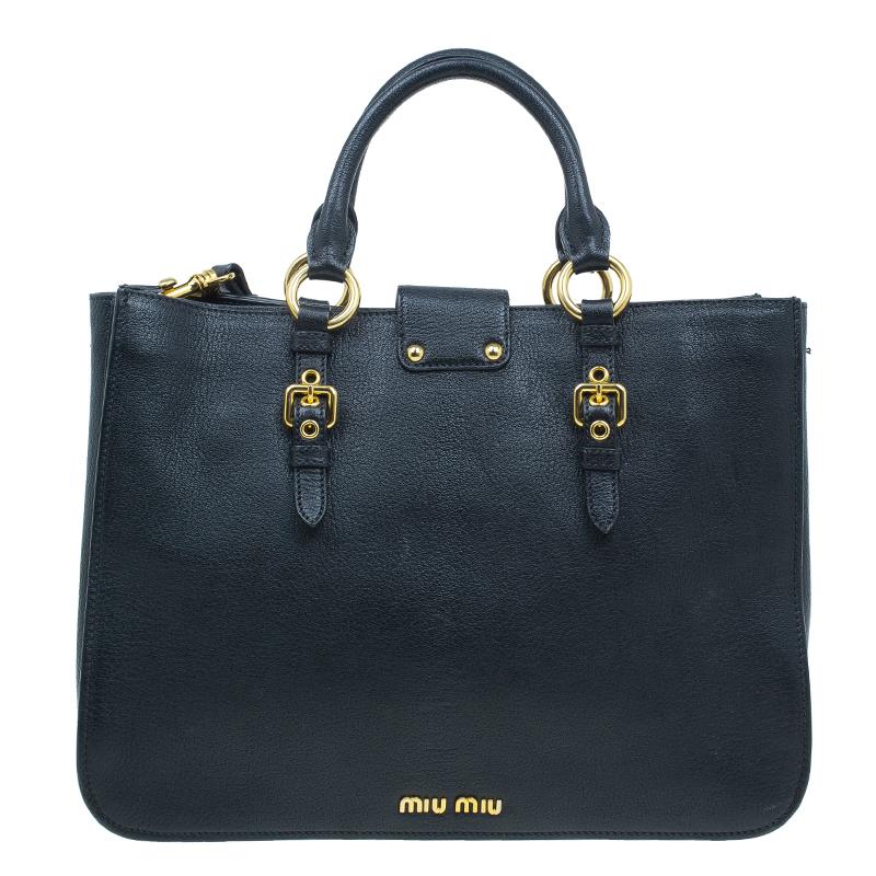 This tote by Miu Miu combines luxury and utility. It is crafted from black leather it come with a front flap accented with a gold-tone push lock closure, rolled leather handles, a detachable and adjustable shoulder strap. The interior is lined with