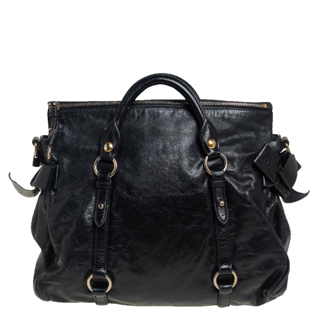Masterfully crafted from Vitello Lux leather and lined with fabric, this satchel from the house of Miu Miu is both stylish and durable. In a subtle shade of black, it flaunts dual top handles and trendy bows detailed on the sides. Equipped with logo