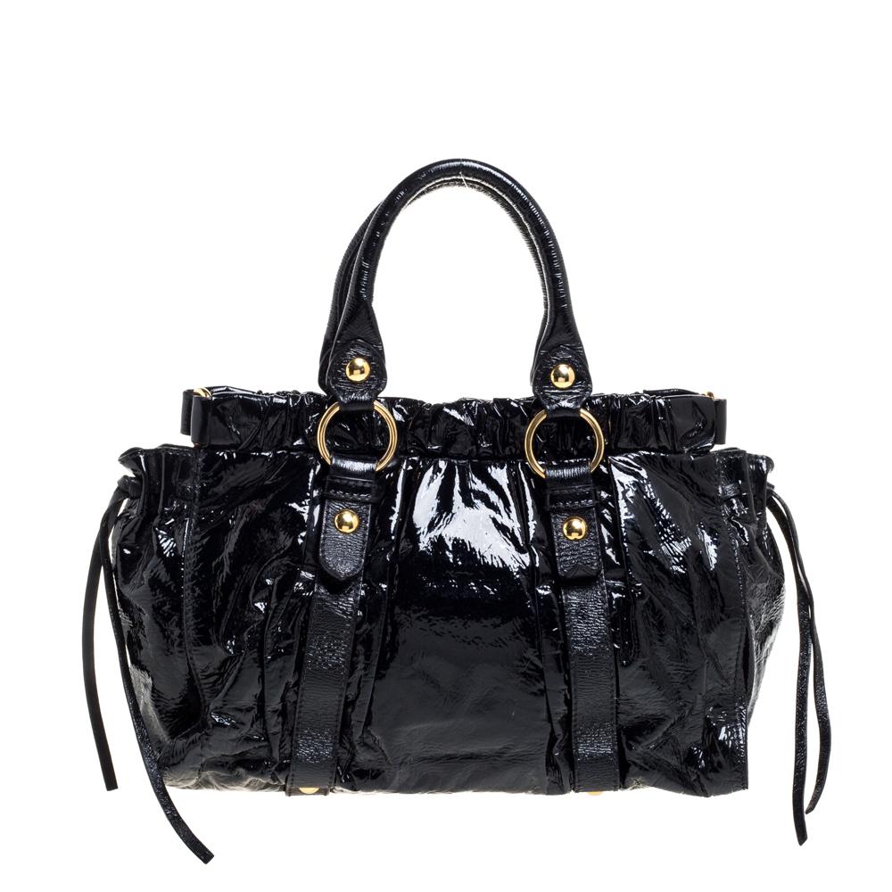 Tombez immédiatement amoureux de ce fourre-tout aux caractéristiques séduisantes signé Miu Miu. Confectionné en cuir verni, ce sac est doté de deux anses supérieures et de ferrures dorées. L'intérieur est doublé de tissu et accueillera toutes vos