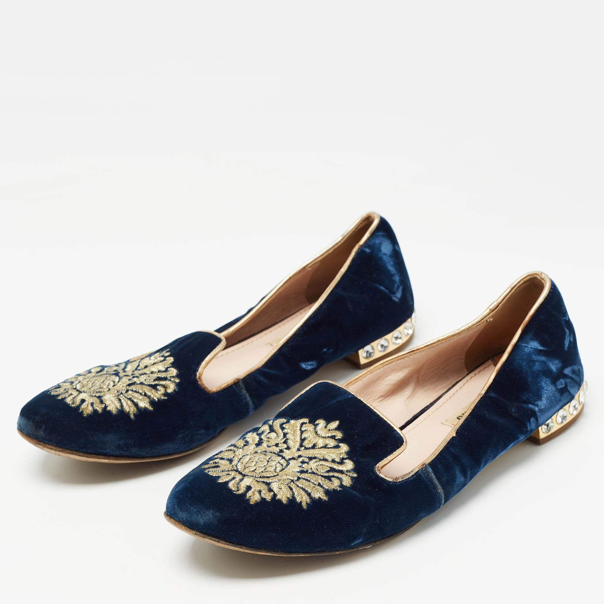 These eye catching smoking slippers by Miu Miu have been crafted in blue velvet. They feature beautiful embellished motifs in go at the vamps. The heels are embellished with crystals. The insoles are leather lined. Fused with formal or casual wear,