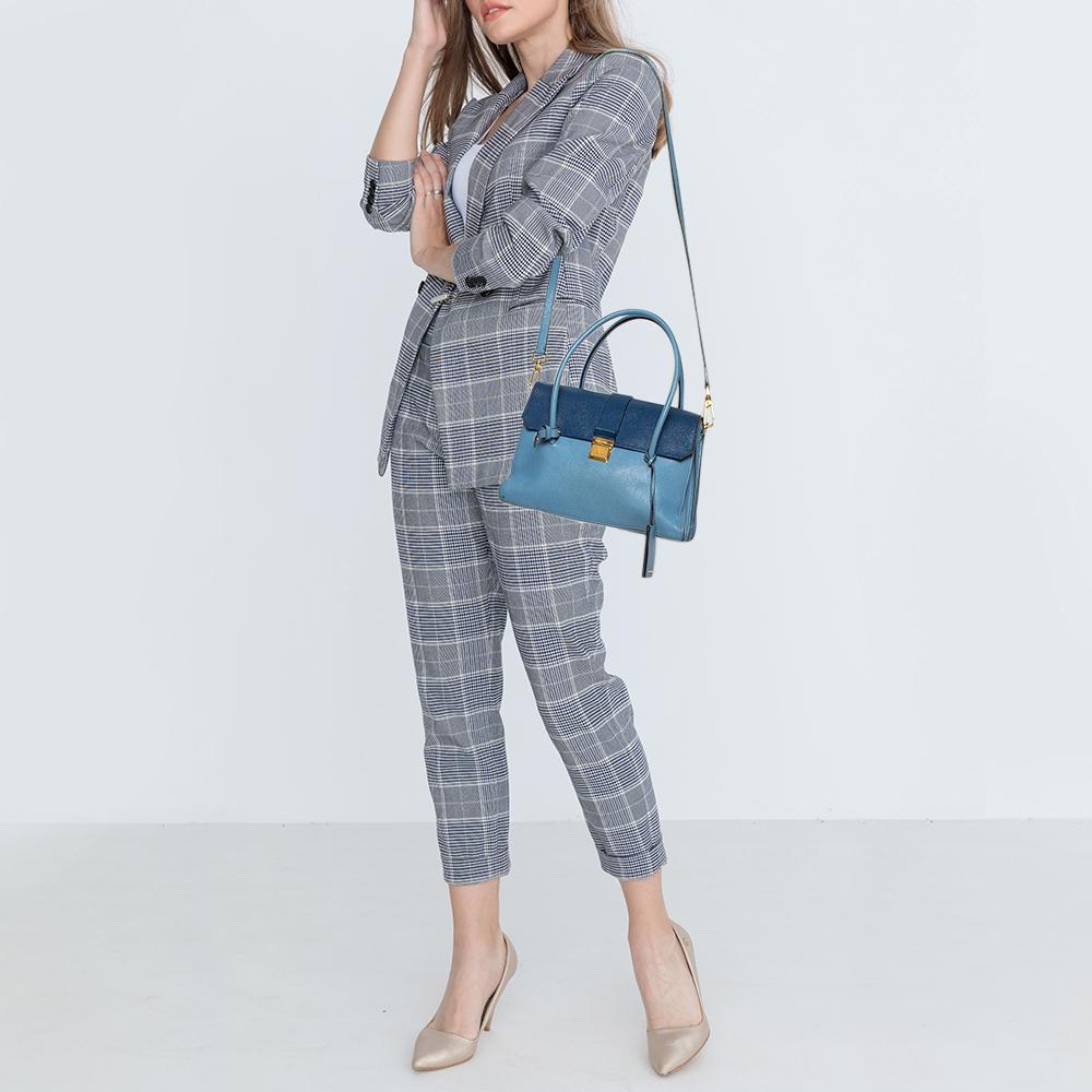 A chic bag for you to step out in style and win compliments! This two-toned blue bag from Miu Miu comes crafted from leather and features a front gold-tone lock detailed flap. It has twin top handles and a detachable shoulder strap and opens to a