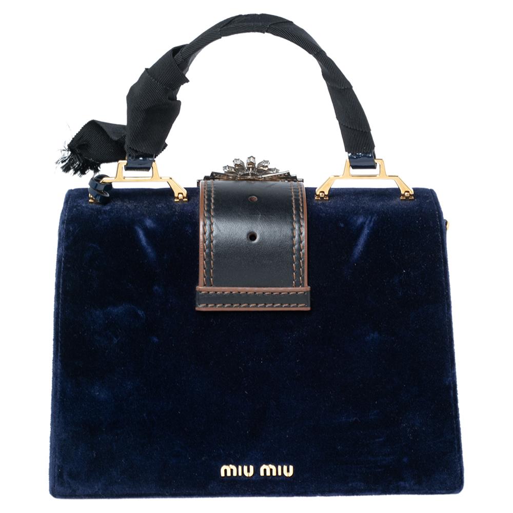 How lovely is this bag from Miu Miu! It has been made from blue velvet on the exterior, with a crystal-embellished buckled flap decorating its structure. It has gold-toned hardware, a top handle, and a satin-lined interior. This Miu Miu bag will