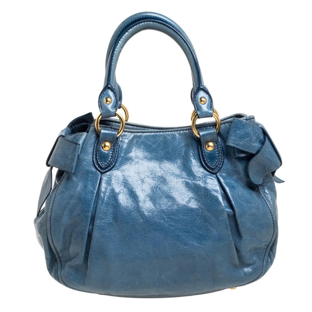 You are going to love owning this bow satchel from Miu Miu as it is well-made and brimming with luxury. The blue satchel has been crafted from Vitello leather and shaped beautifully. It has a well-sized satin-lined interior with a zip pocket, and it