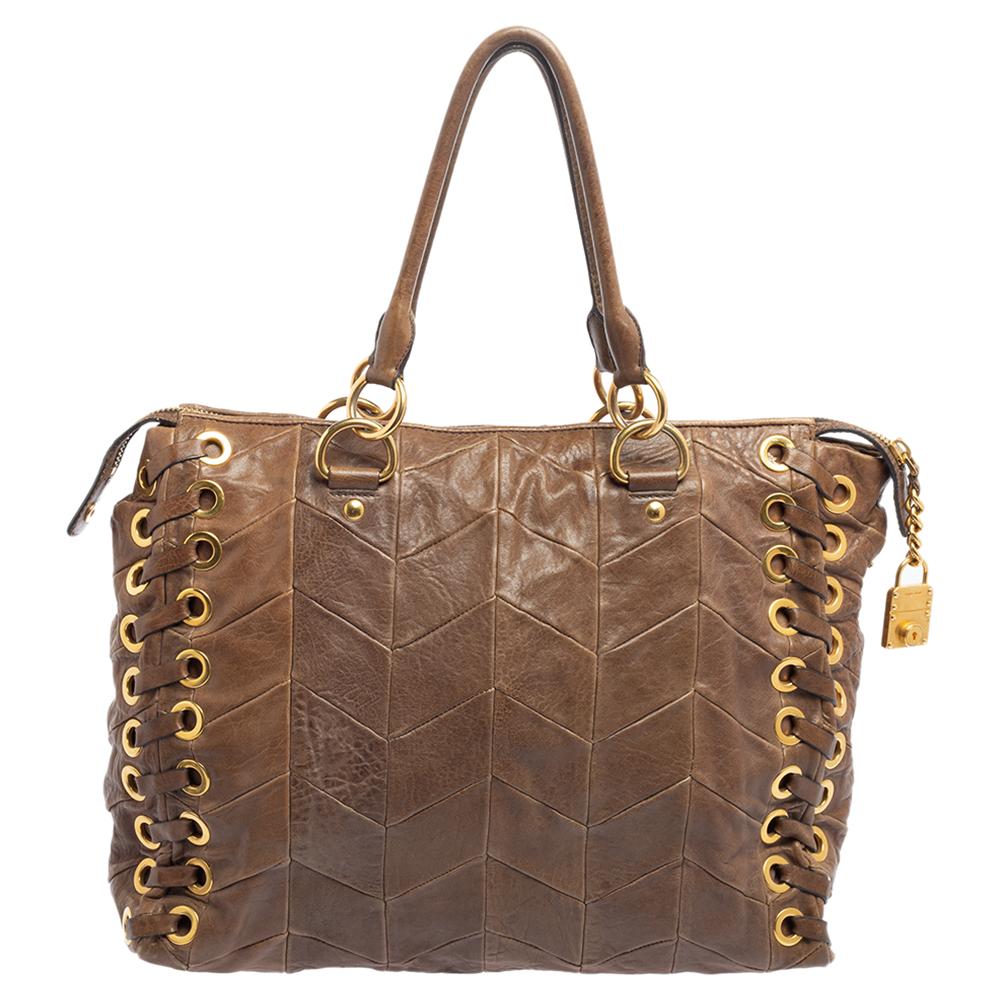 This Miu Miu leather bag is a fine accessory to get your hands on. It is made from brown chevron leather with the brand logo on the front and gold-tone grommet detailing. It features top handles, top zipper closure, and a spacious satin-lined