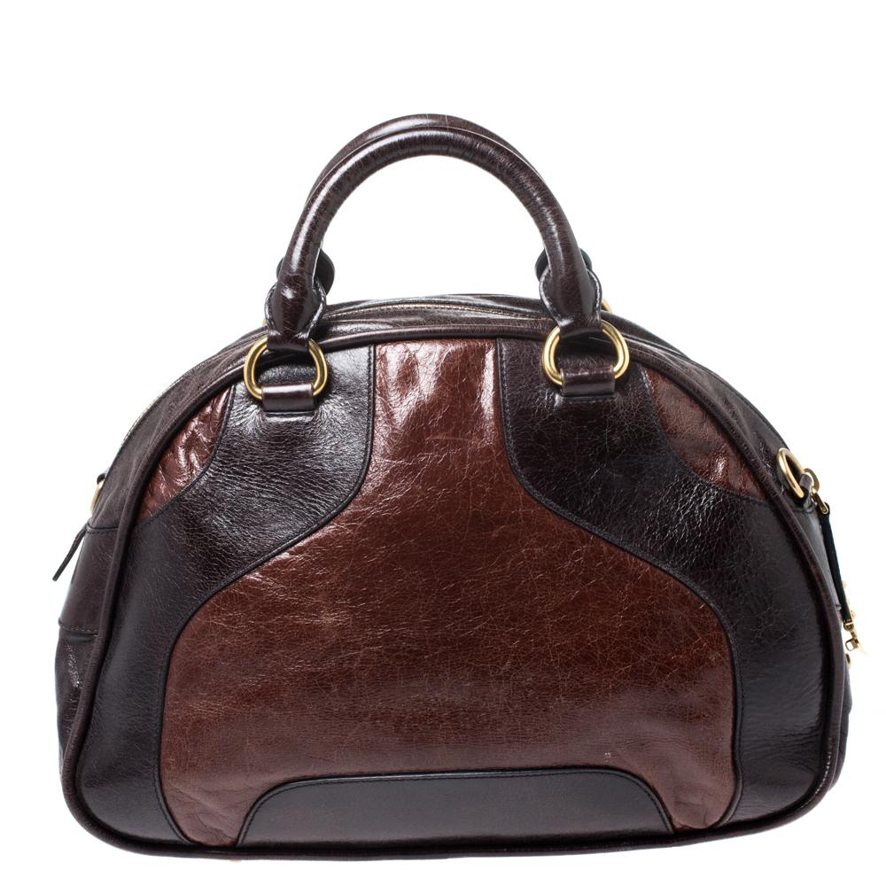 This stunning bowler bag comes from the house of Miu Miu. It is crafted meticulously from quality leather and comes in lovely hues of brown. It has a sophisticated silhouette, features dark brown leather trims, brand logo, dual handles, zi[p closure