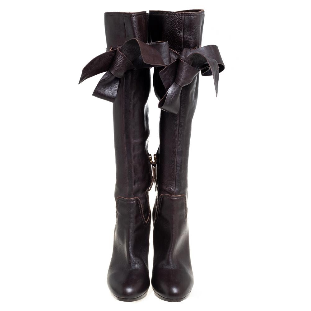 Diese kniehohen Stiefel von Miu Miu sind der Inbegriff von Chic und mühelosem Stil. Sie sind aus braunem Leder gefertigt und haben eine runde Fußspitze. Sie sind mit einer Schleife und einer bequemen ledergefütterten Innensohle ausgestattet. Sie