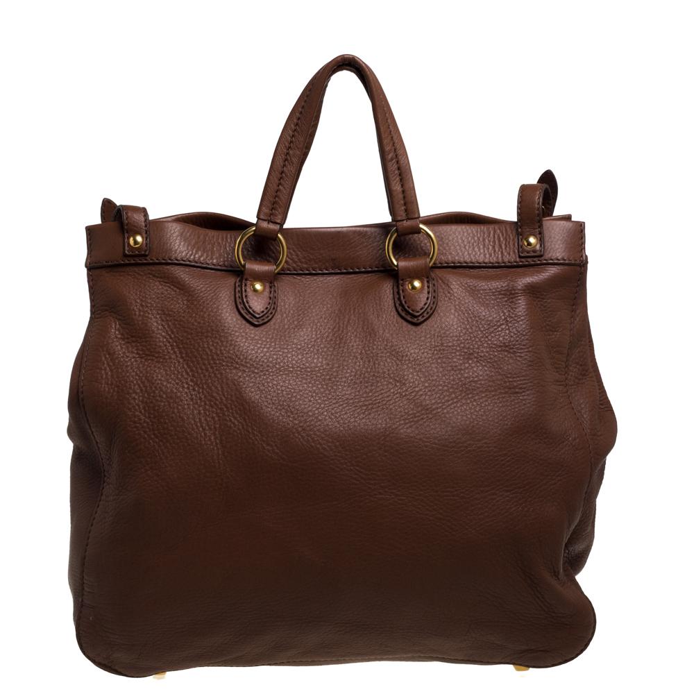 This shopper tote from Miu Miu is a timeless piece. The bag comes with a luxurious brown leather exterior and has a gold-tone brand logo and double buckle straps detailed on the front. It features dual top handles and protective metal studs at the