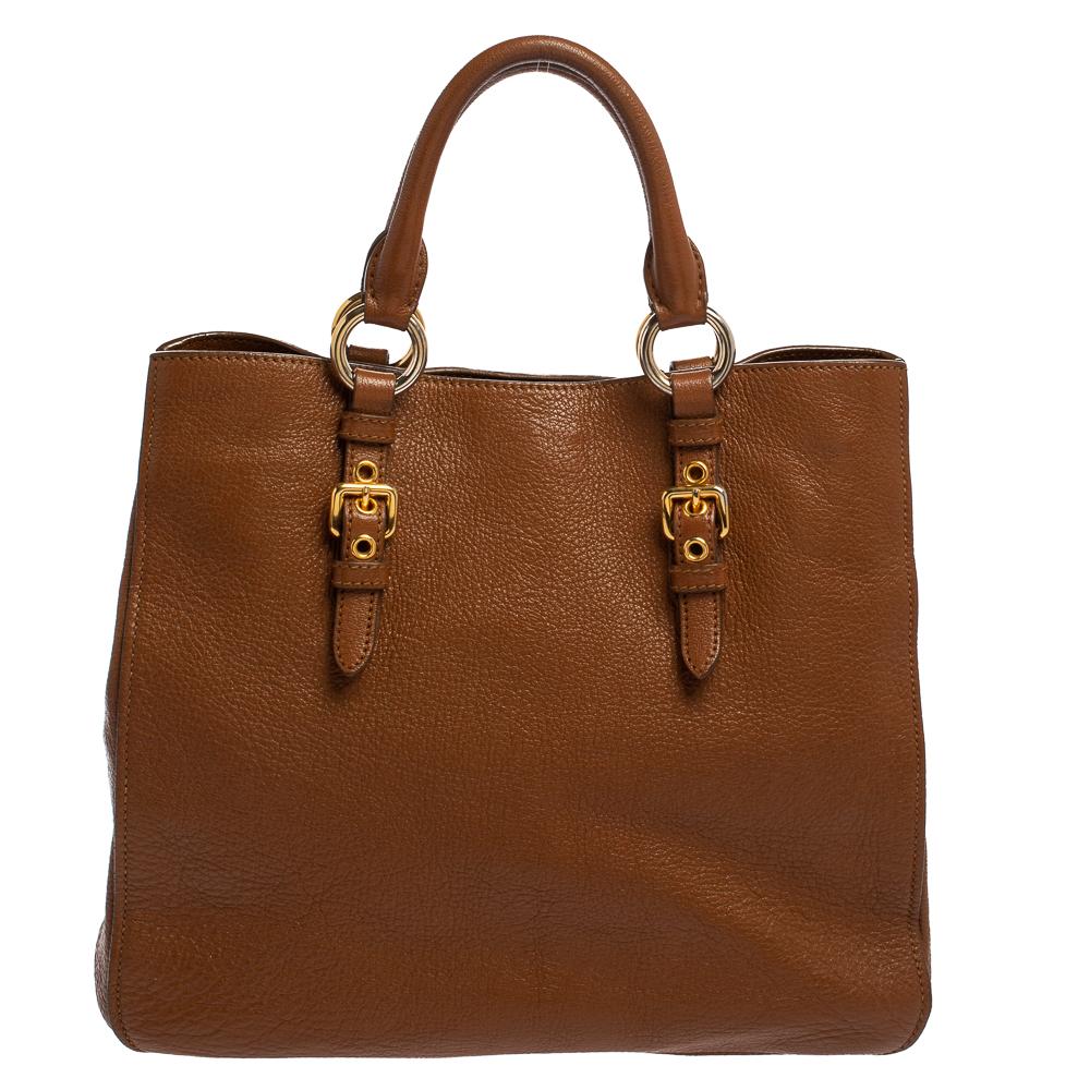Stunning to look at and durable enough to accompany you wherever you go, this Miu Miu tote bag is a joy to own! This Madras bag is crafted from leather in a brown shade and is highlighted by gold-tone hardware. Held by dual handles, the creation is