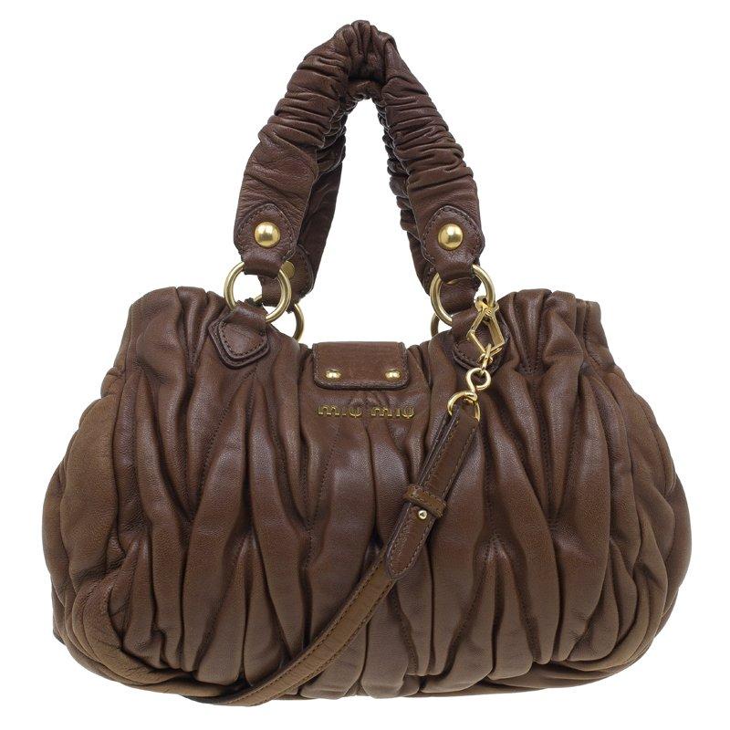 Flaunt it in style as this Miu Miu tote has all the elements to augment your oomph factor. Crafted in matelassé leather in brown, it features ruffled finish, two braided top handles, and a detachable shoulder strap. It comes with expandable side