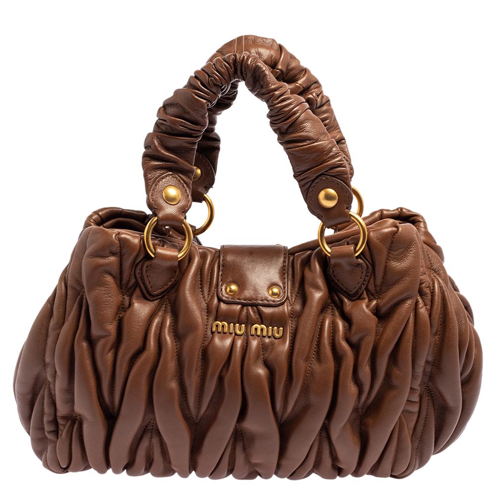 Flaunt it in style as this Miu Miu tote has all the elements to augment your fashion sense. Crafted in matelassé leather in brown, it features a ruffled finish, two handles, and a detachable shoulder strap. It comes with expandable side snaps and a