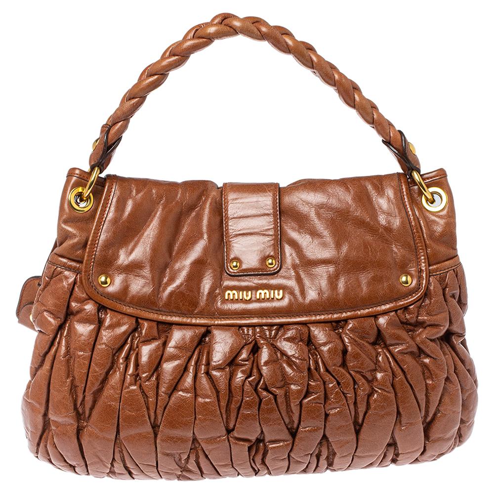 This chic and feminine Coffer bag is from Miu Miu. It is crafted from Matelasse leather and features a flap secured with a gold-tone push-lock closure. The bag opens up to a satin-lined interior sized to fit your daily essentials. The brown creation