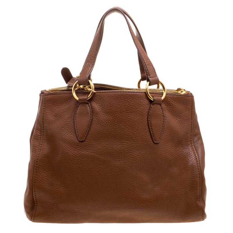 This tote by Miu Miu is a piece all fashionistas must look out for! Meticulously crafted from pebbled leather, it features a brown shade as well as two handles and a shoulder strap for you to parade it. The bag is equipped with a spacious