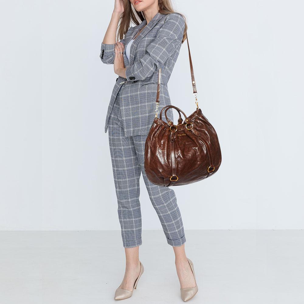 Miu Miu brings you this lovely gathered hobo that has been crafted from Vitello Shine leather. It has a well-sized satin interior and the bag is complete with two top handles and a shoulder strap. Stylish and ideal for daily use, this bag is a