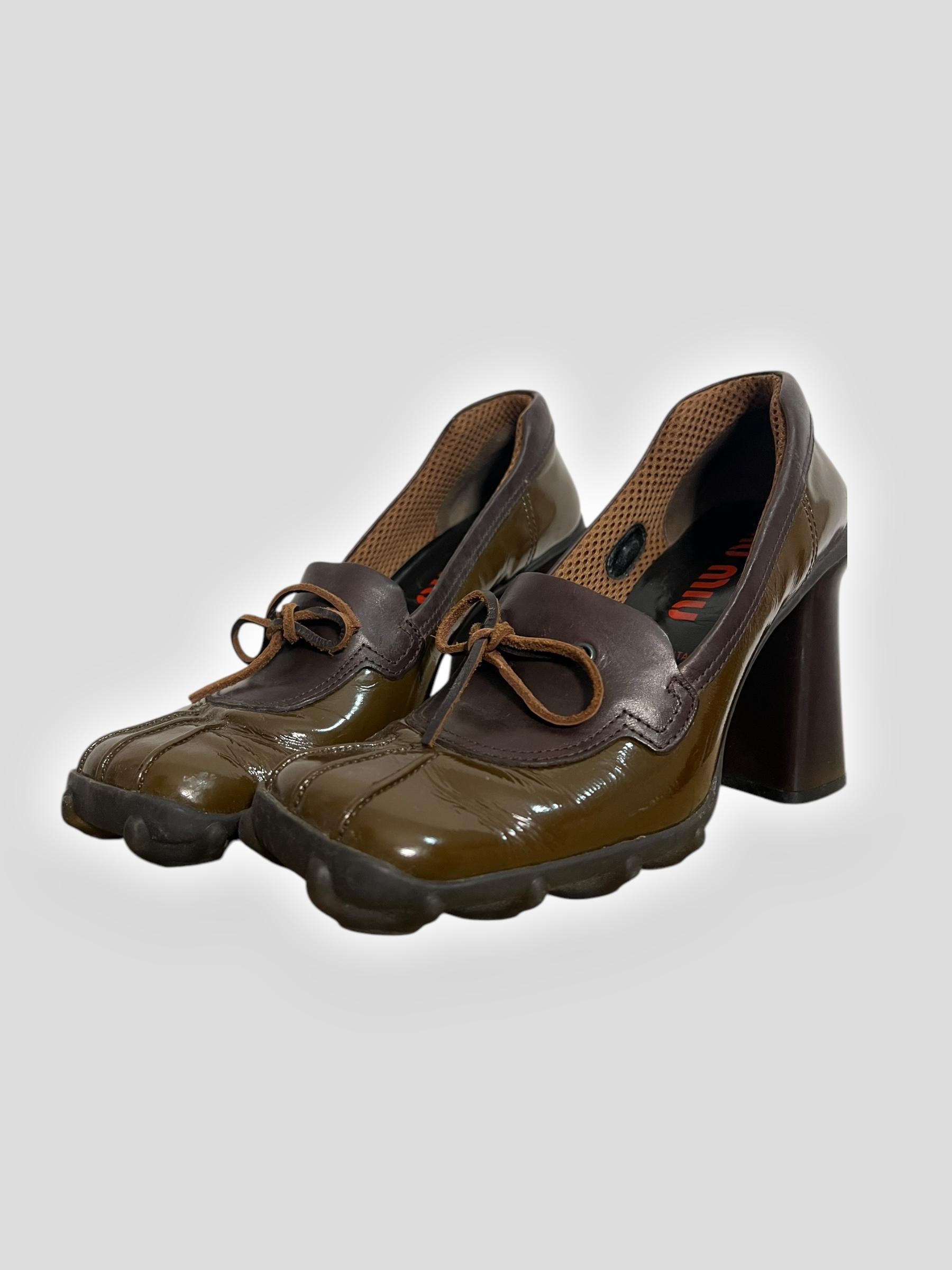 A bold and futuristic design from Miu Miu’s 1999 collection, these patent heels feature the brand’s signature bubble sole, adding a playful yet functional touch. The deep olive-green patent leather contrasts with brown leather trim and delicate