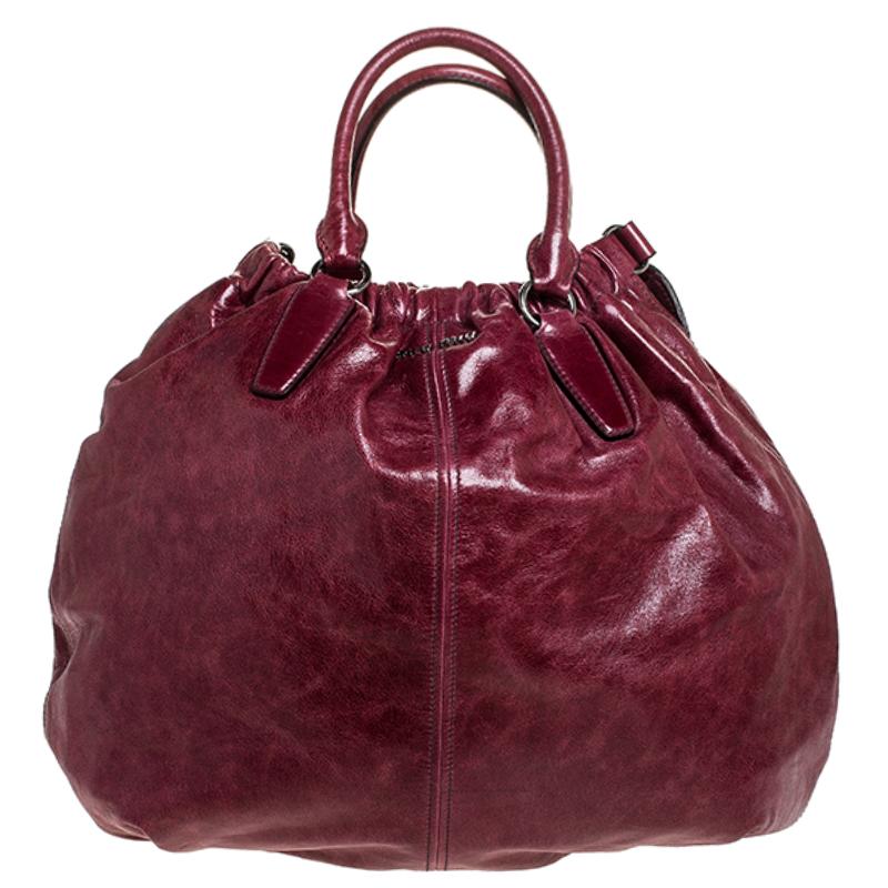 A flawless addition to your collection is this hobo in a shade of burgundy from Miu Miu. Masterfully crafted from leather, this bag can easily hold more than just essentials. This hobo comes with dual handles, a pocket on the front and is the