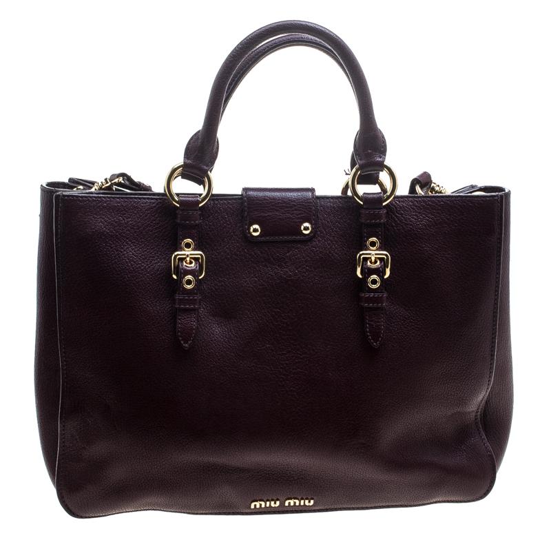 This Madras Executive tote by Miu Miu combines luxury and utility. It is crafted from burgundy leather with a front Miu Miu push-lock closure, rolled leather handles, a detachable and adjustable shoulder strap and gold-tone hardware. The interior is