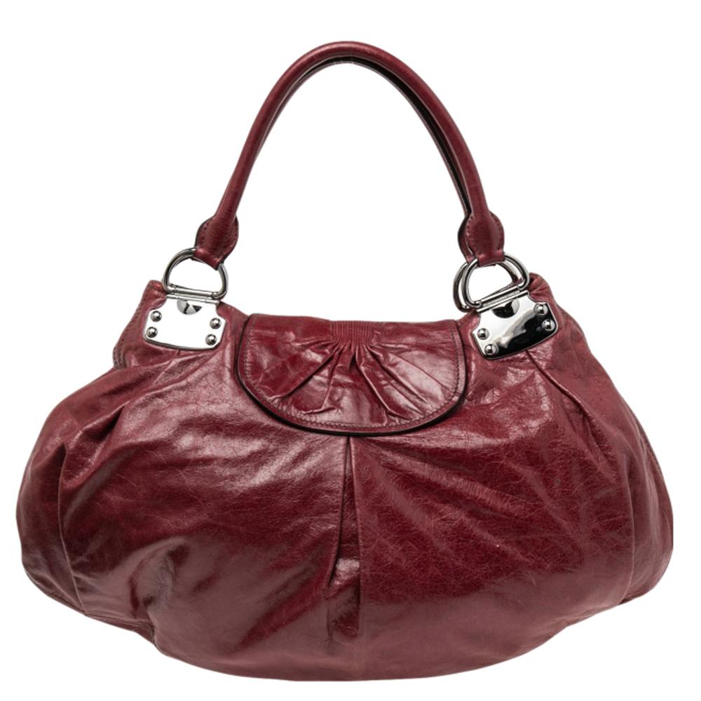 This lovely bag comes from the house of Miu Miu. Crafted from quality leather, it flaunts a lovely shade of burgundy. The exterior is beautified with silver-tone hardware. The bag opens to reveal a spacious fabric interior. This bag will make sure