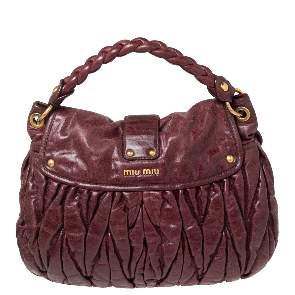 Miu Miu's coffer hobo is crafted from burgundy matelassé leather. The bag features a braided top handle, a detachable shoulder strap, and gold-tone hardware. The metal lock opens to a spacious satin-lined interior.

Includes: Strap