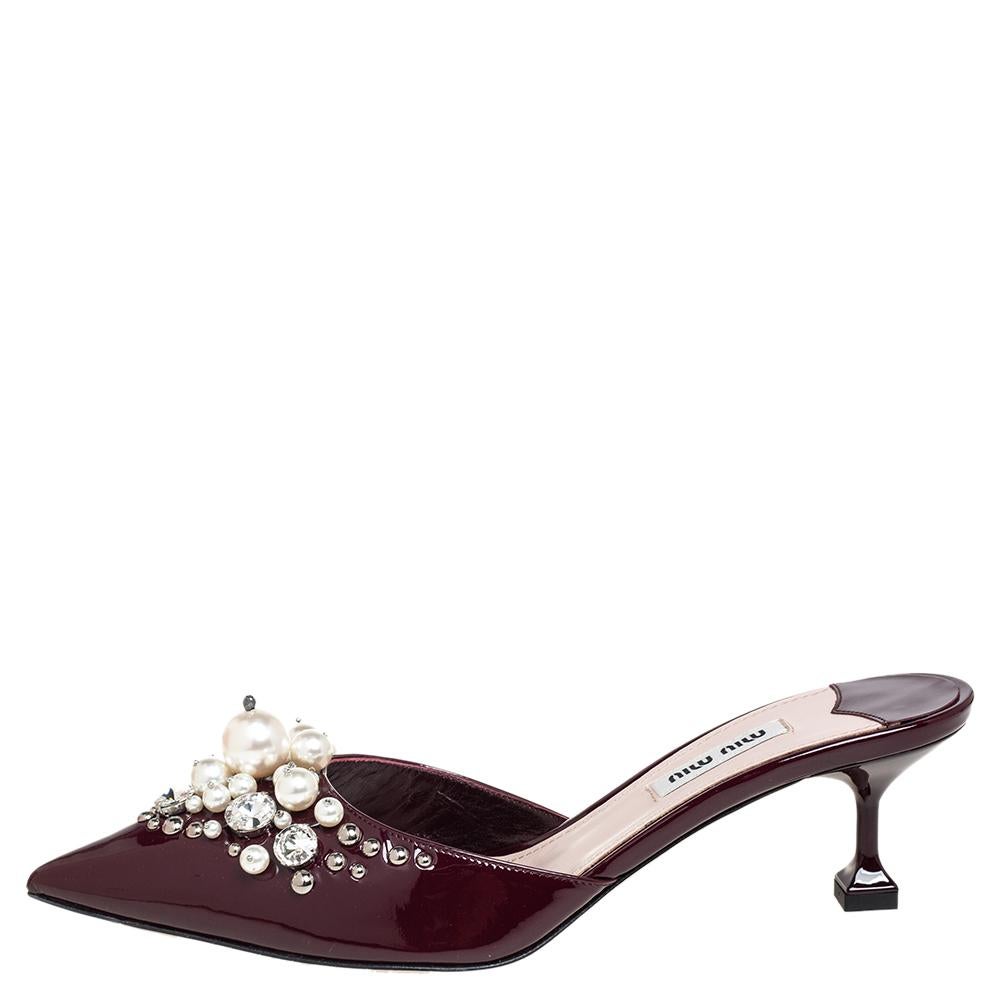 These mule sandals from Miu Miu are designed for the fashionable you! Patent leather is used to create a pointed-toe silhouette and the burgundy shade with dazzling pearl and crystal embellishments lend the mules a distinctive look. The comfortable