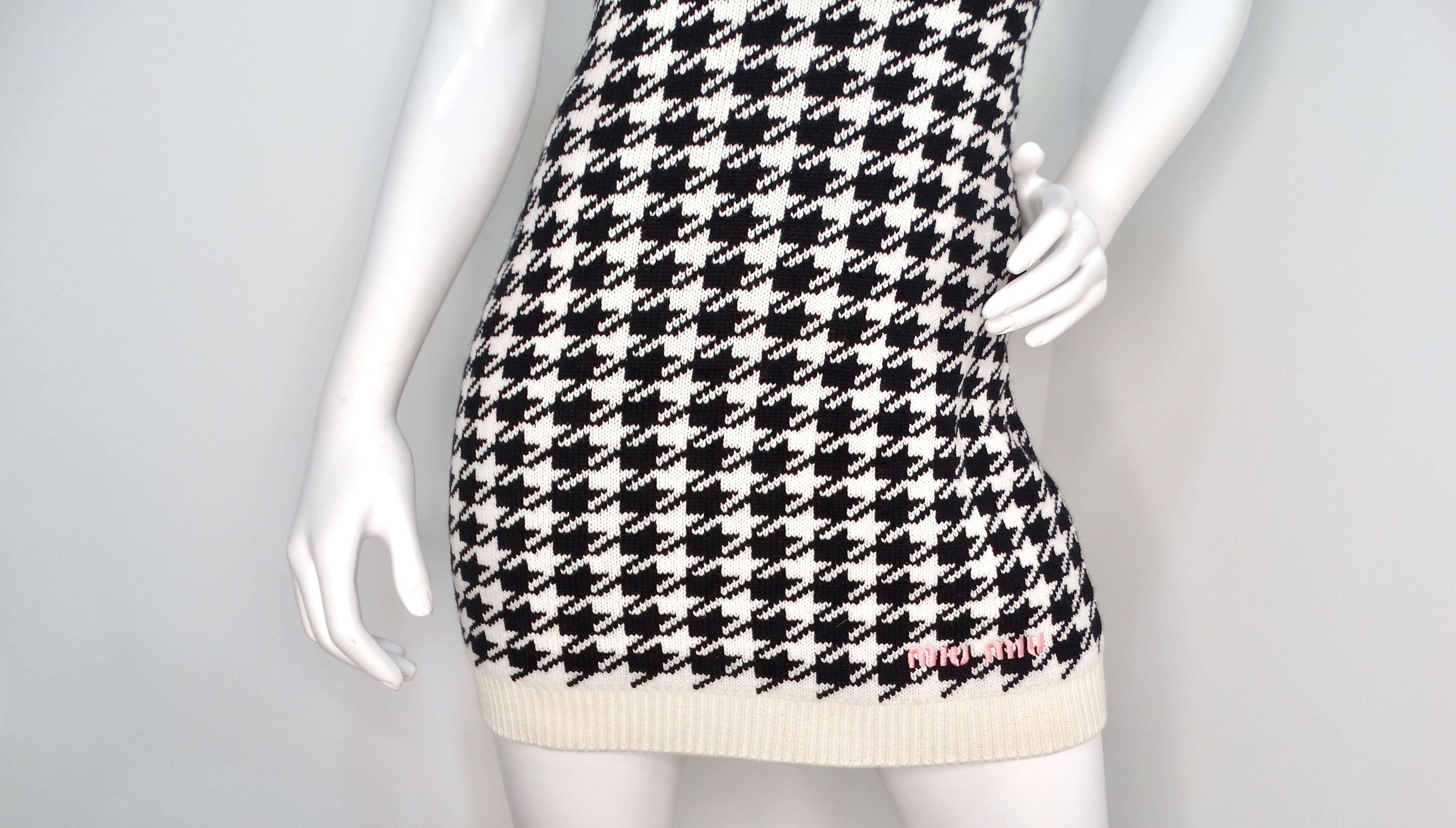The Miu Miu Cashmere Mini Houndstooth Sleeveless Dress is a chic and sophisticated piece that effortlessly combines comfort with high fashion. Crafted from luxurious cashmere, this dress features a classic black and white houndstooth pattern,