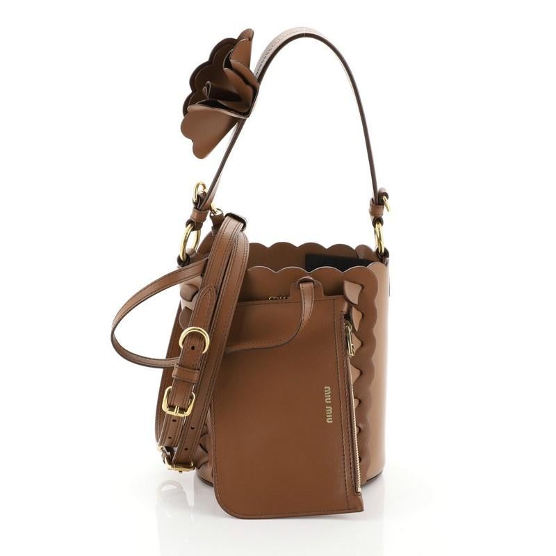 This Miu Miu Convertible Bucket Bag Leather with Applique Small, crafted in brown leather, features a leather top handle with floral-appliquéd, scalloped edges and gold-tone hardware. It opens to a brown leather interior. 

Estimated Retail Price: