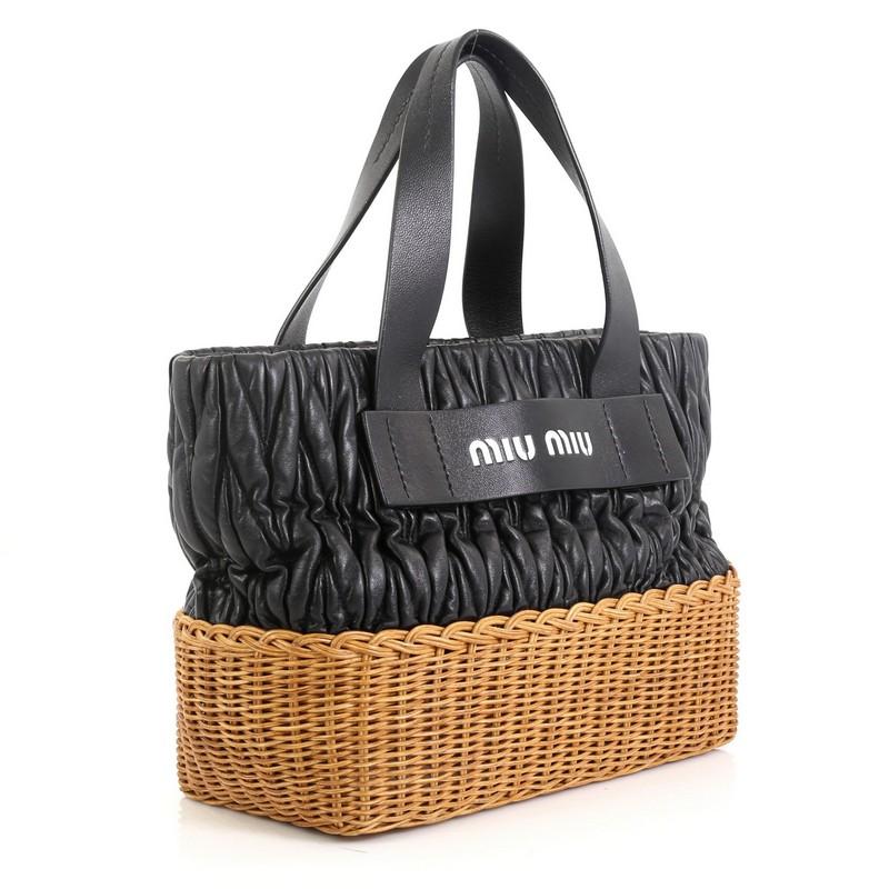 This Miu Miu Convertible Bucket Tote Matelasse Leather and Wicker Medium, crafted in black leather and neutral wicker, features dual flat leather handles, and silver-tone hardware. It opens to a black fabric interior with zip and slip