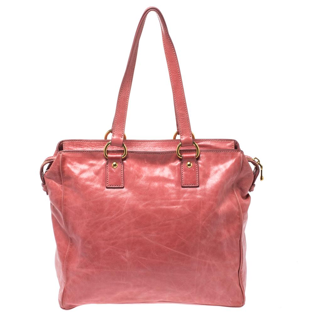 This Miu Miu satchel bag is chic, stylish and one of a kind. Crafted meticulously from cracked leather, it's exterior flaunts a lovely shade of coral. It is styled with dual handles, an exterior zip pocket and the brand logo. The interior is lined