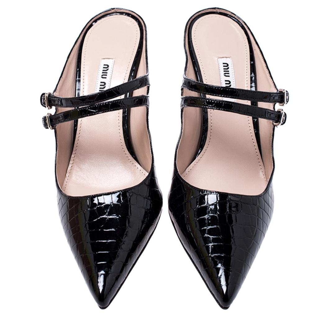 Pick this gorgeous pair of mules and flaunt your style. This pair from the house of Miu Miu is made from black croc-embossed patent leather and feature two buckled straps over the vamps, pointed toes and slim heels. Have a striking day out in these