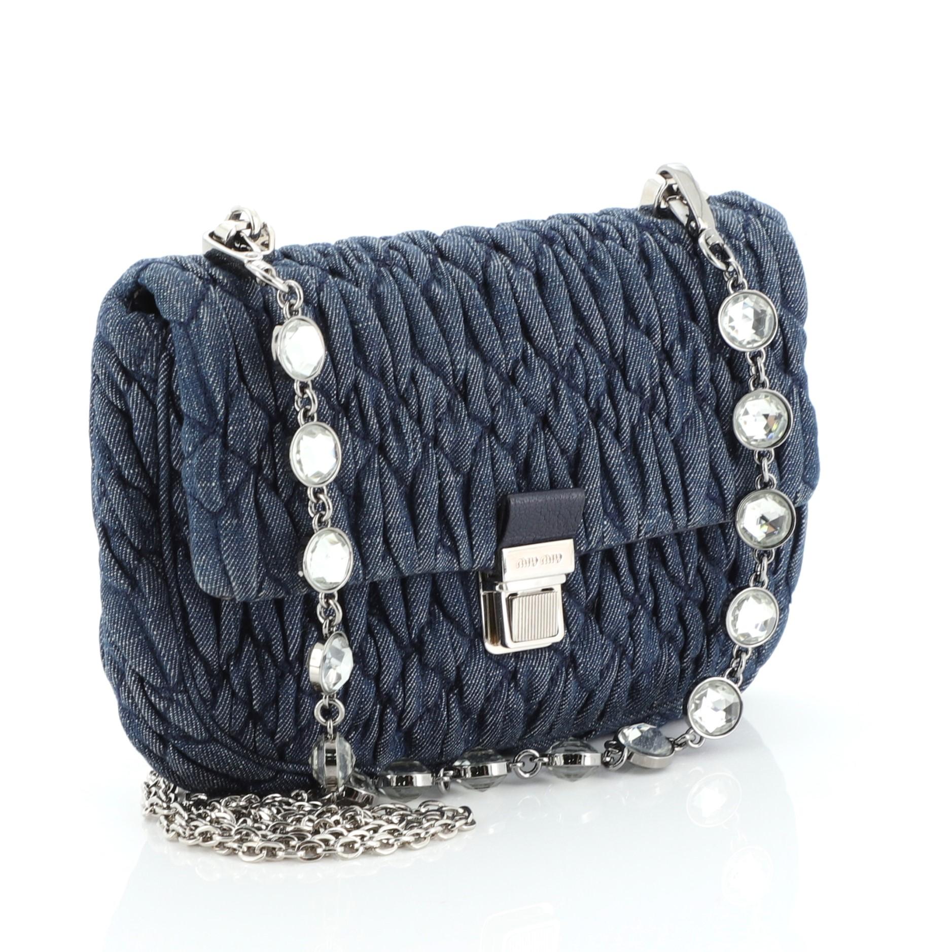 This Miu Miu Crystal Shoulder Bag Matelasse Denim Medium, crafted in blue matelasse denim, features a chain and crystal strap, frontal flap and silver-tone hardware. Its push-lock closure opens to a blue leather and fabric interior with side slip