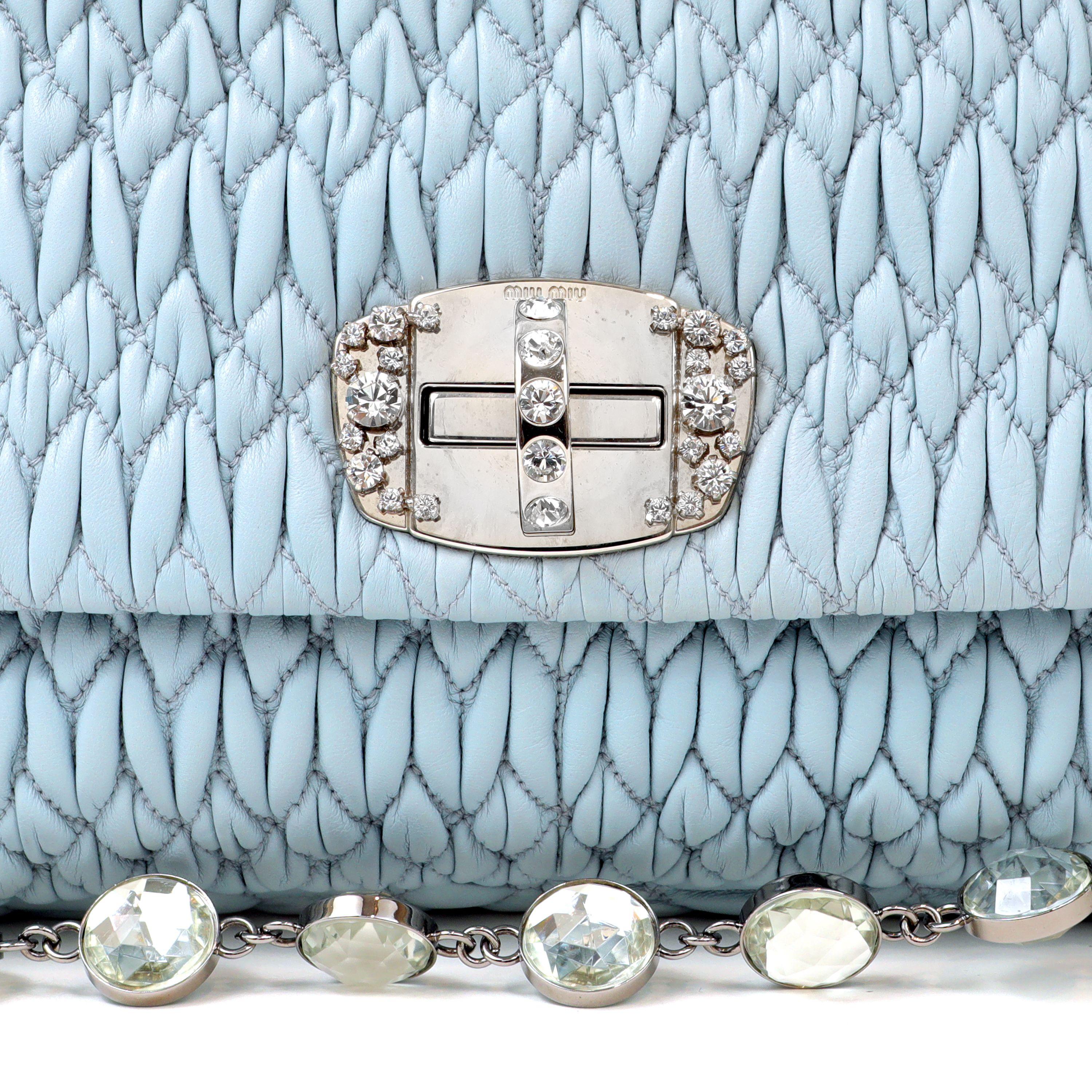 This authentic Miu Miu Powder Blue Crystal Cloquè Large Bag is in pristine condition.  The iconic design features light blue raised quilted Nappa leather with silver and crystal turn lock closure.  May be carried by the detachable leather strap or