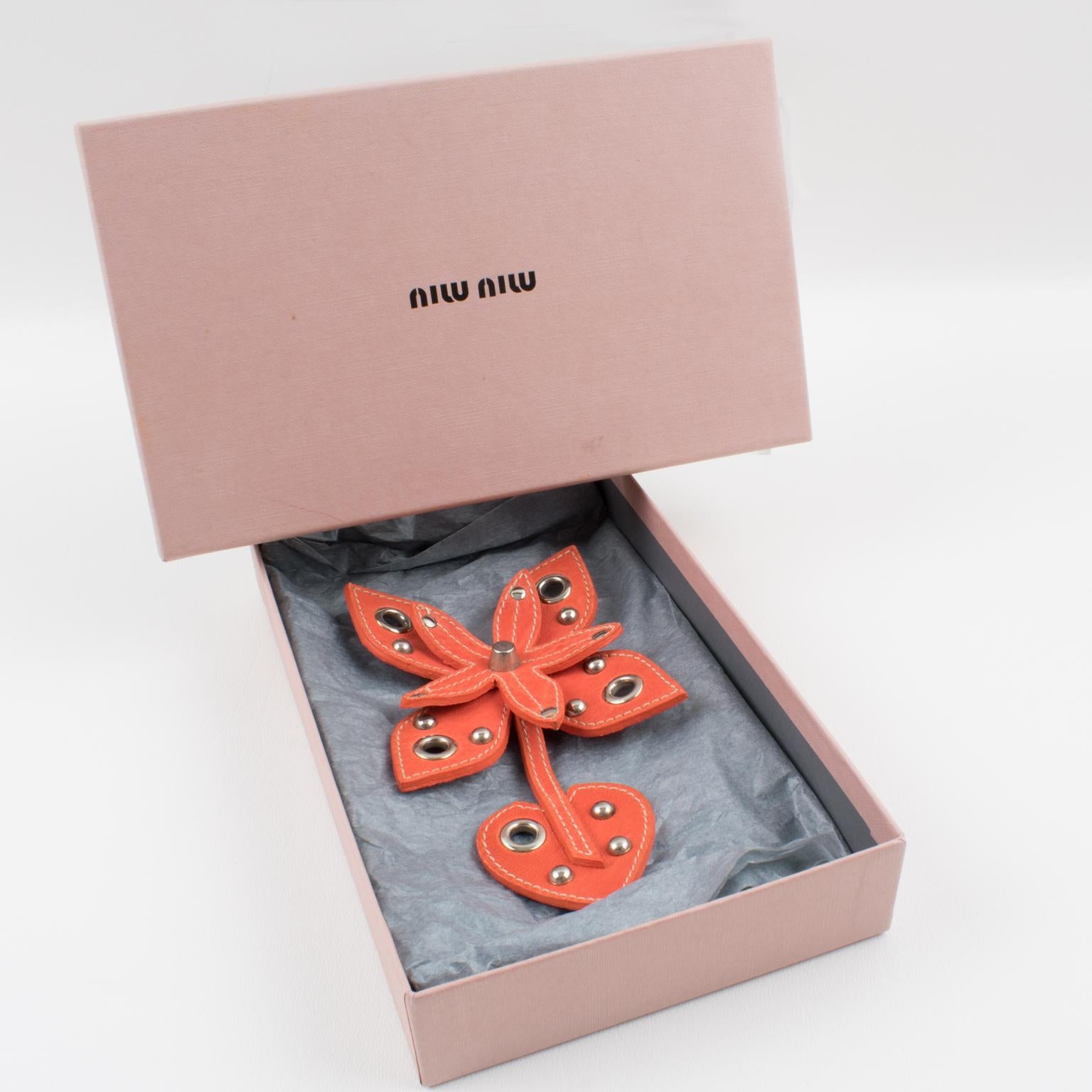 This adorable Miu Miu naturalist leather pin brooch features a giant stitched tangerine orange leather stylized flower shape ornate with stainless steel studs and eyelets. The piece is marked on the underside with the Miu Miu - made in Italy tag.