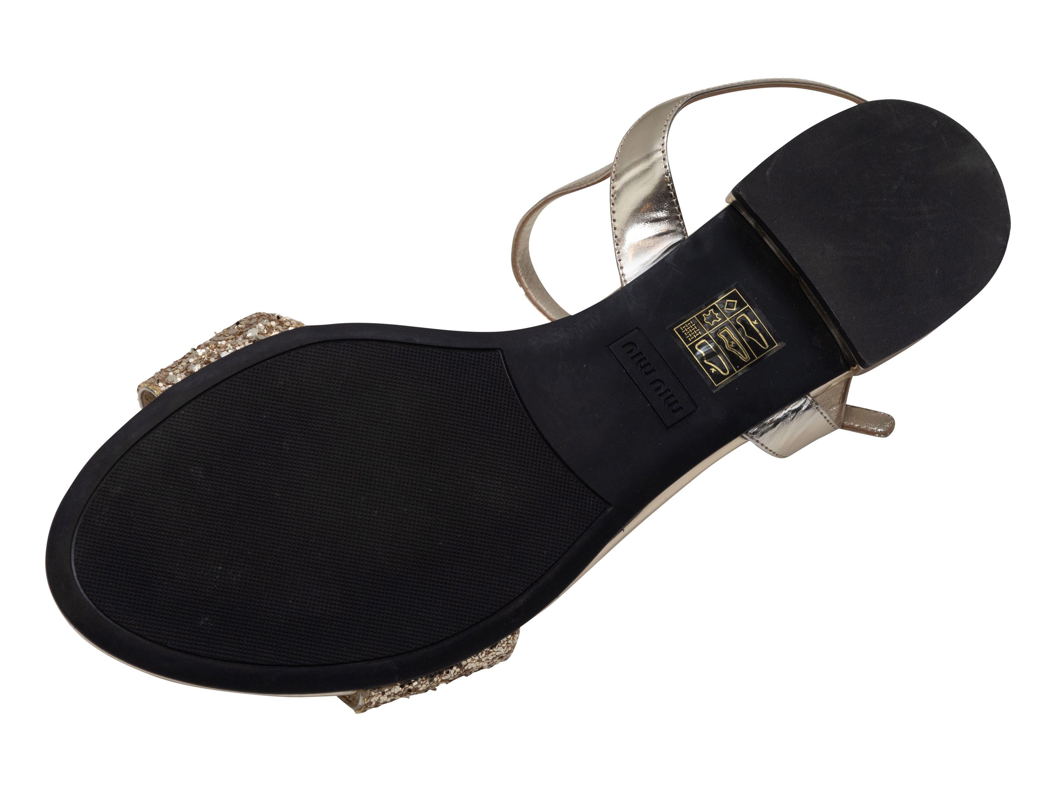Product Details: Gold glitter flat sandals by Miu Miu. Buckle closures at ankle straps.

Designer Size: 40
US Recommended Size: 10

Condition: Pre-owned. Good. Wear at soles. Scratch at toe
