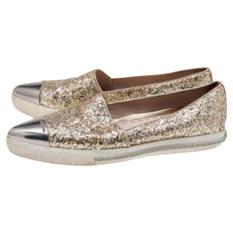 Ces baskets de la maison Miu Miu sont synonymes de classe et de luxe. Ces baskets à enfiler sont créées à l'aide de paillettes dorées et de métal sur l'extérieur. Ils sont dotés de bouts pointus et d'une quincaillerie argentée. Ces baskets Miu Miu