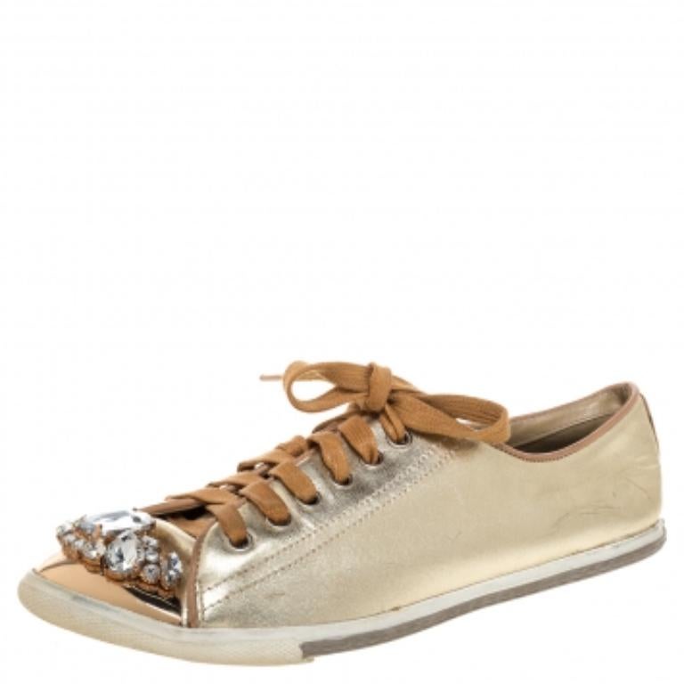 Who says sneakers cannot have a touch of sparkle? These Miu Miu sneakers are brilliantly crafted from gold-hued leather and detailed with lace-ups and crystals. They are set on comfortable rubber soles and makes a great pair to dresses and skirts