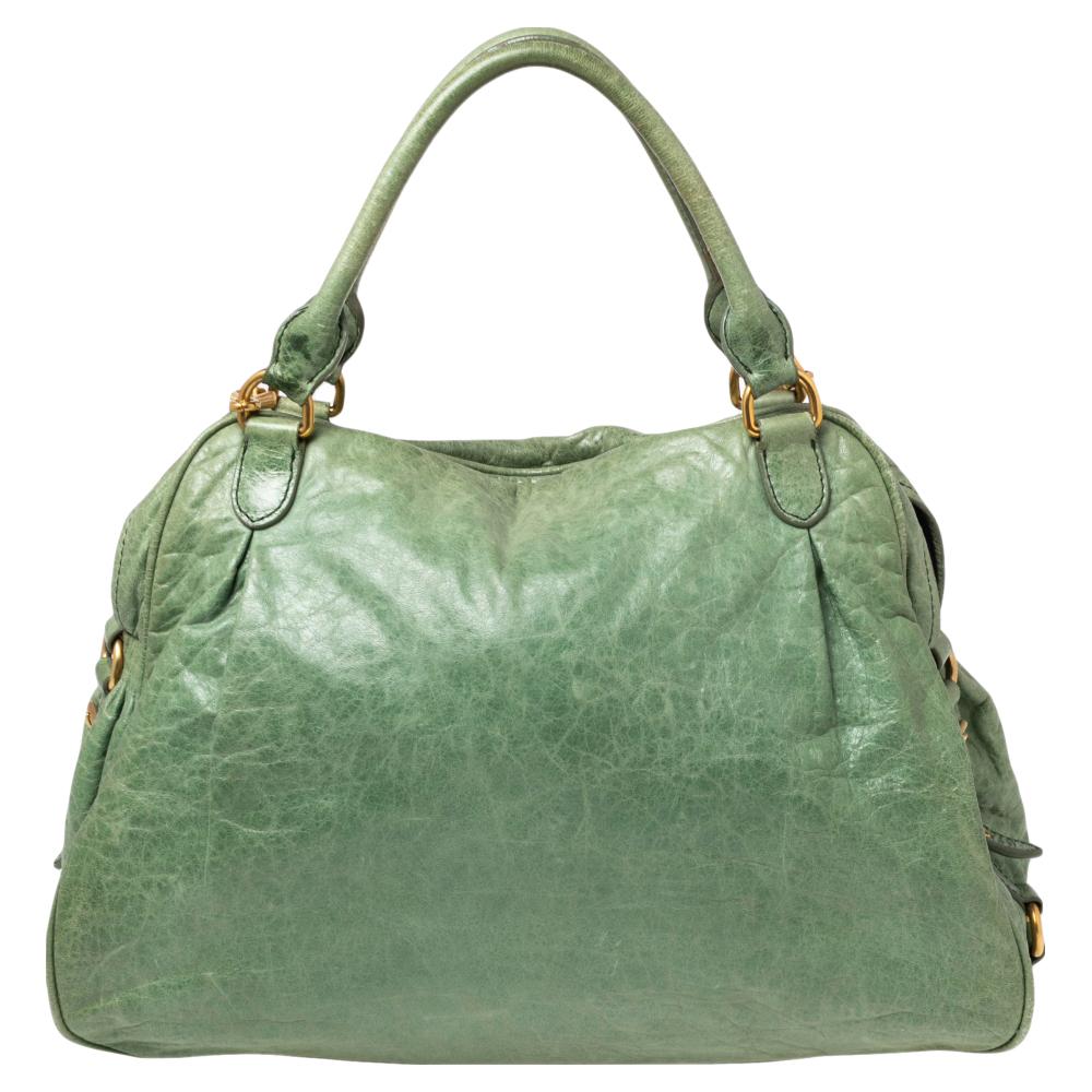 From the House of Miu Miu, this Charm satchel is here to elevate your appearance and make you look stunning. It is made from green leather with a gold-toned charm hanging down the front. It has dual handles, gold-toned fittings, and a shoulder