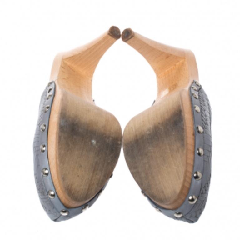 Made in Italy, these platform clogs by Miu Miu are made from grey leather. The uppers are styled with a woven style and punctuated with large studs attached to the midsole. They have wooden platforms and 12.5 cm high block heels. It is finished with
