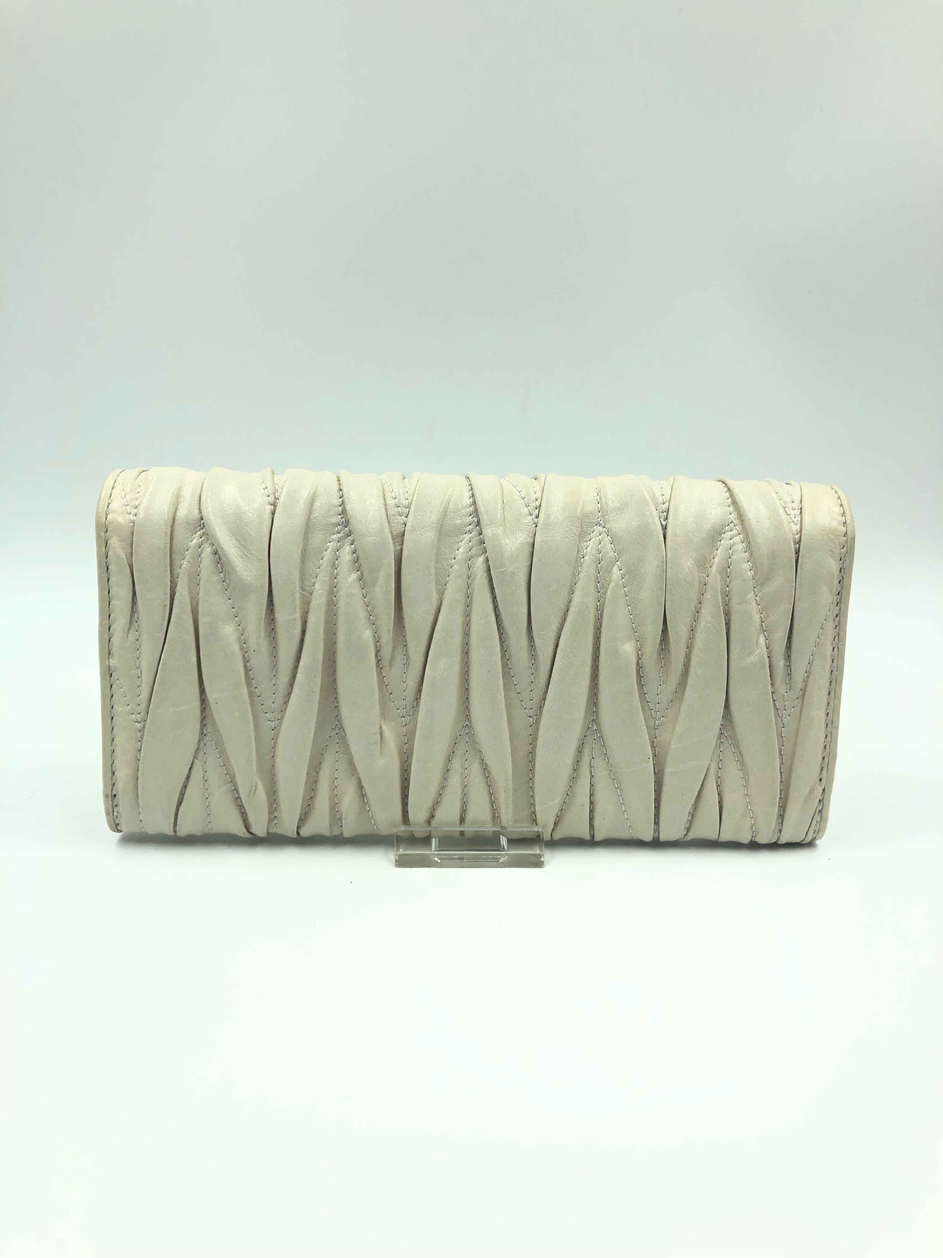 Miu Miu Ivory Matelassé Leather Lambskin Wallet. Signed Miu Miu in gold metal letters on top flap. Middle zipper compartment for change. Wallet comes with original box. Wallet shows no signs of use.
7.5
