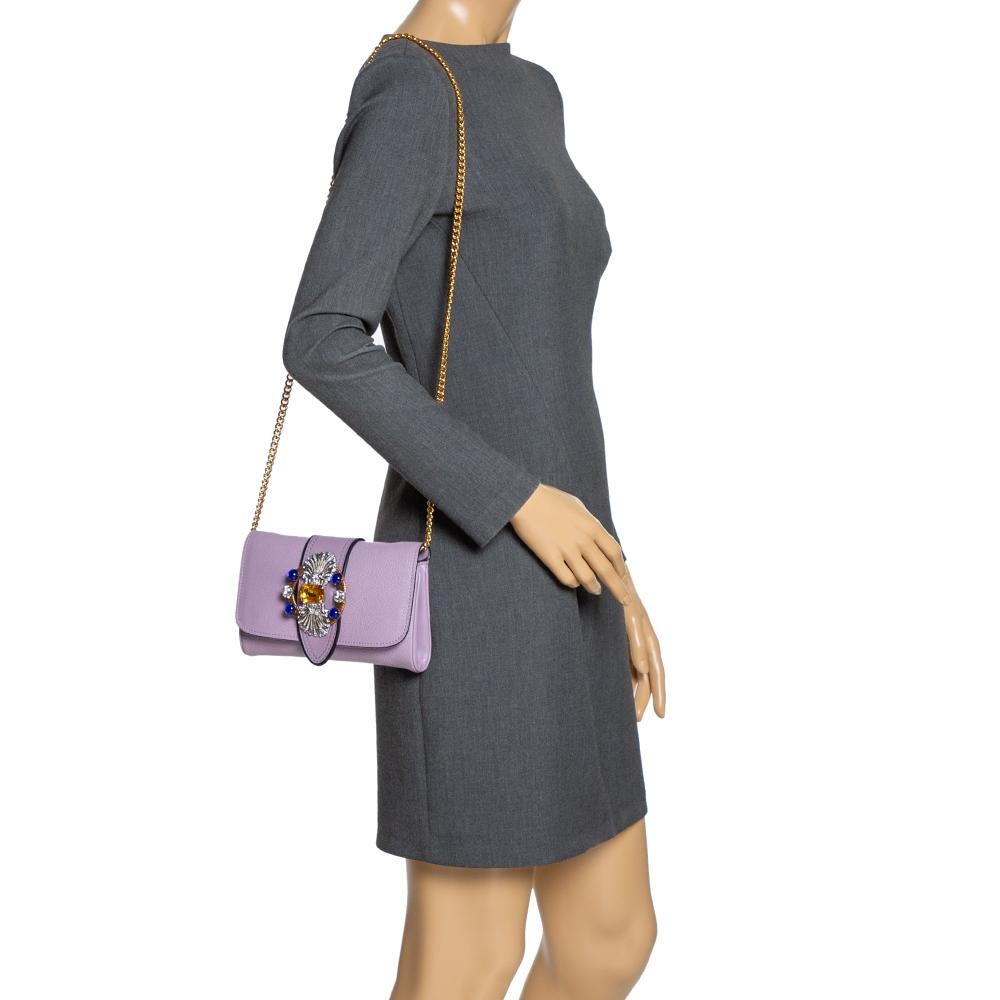 To make a brilliant vogue statement, this handbag by Miu Miu is just what you need! Make an amazing appearance by adorning this rich and classy leather bag. It has a lavender hue, a crystal-embellished flap that leads to a satin-lined interior. It