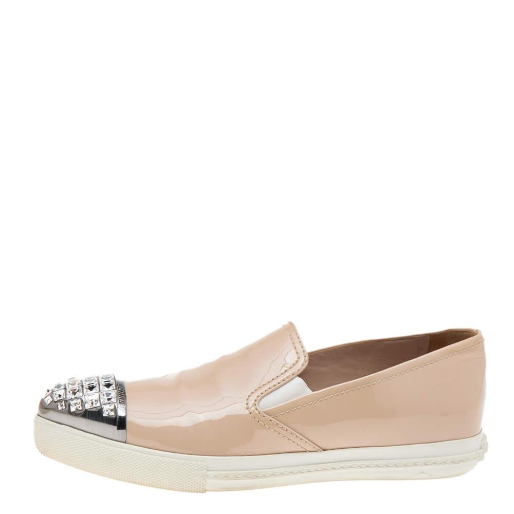 These slip on sneakers from Miu Miu have been crafted from patent leather and feature pointed cap toes embellished with crystals. They come equipped with comfortable leather lined insoles and tough rubber soles.